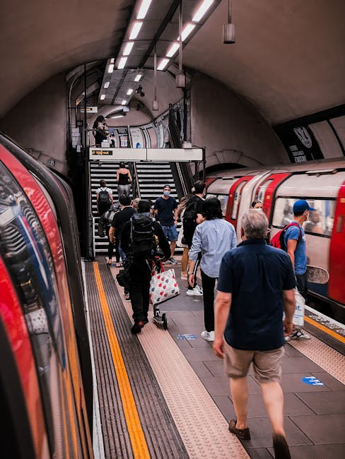 A covered platform at Kennington station featuring a concrete floor and blue-painted steel columns supporting a weathered, corrugated metal roof. The platform is clean and free of litter, with tactile
